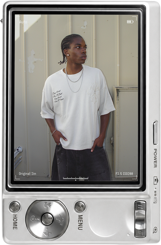 A person in a white shirt stands against a beige wall, looking thoughtfully.