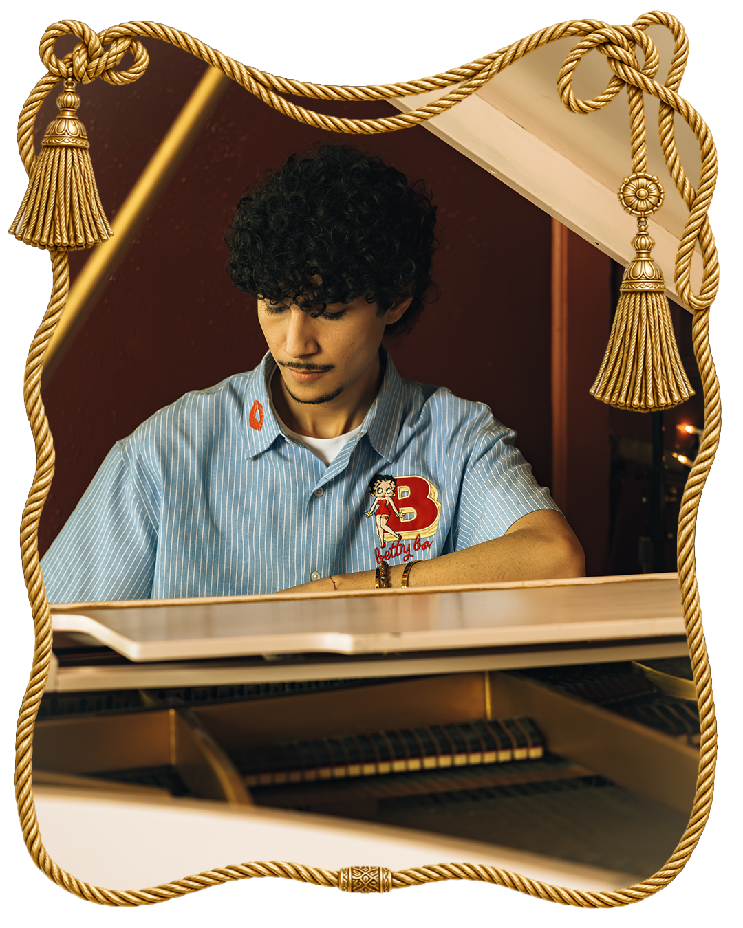 Person playing a piano, framed with decorative tassels.