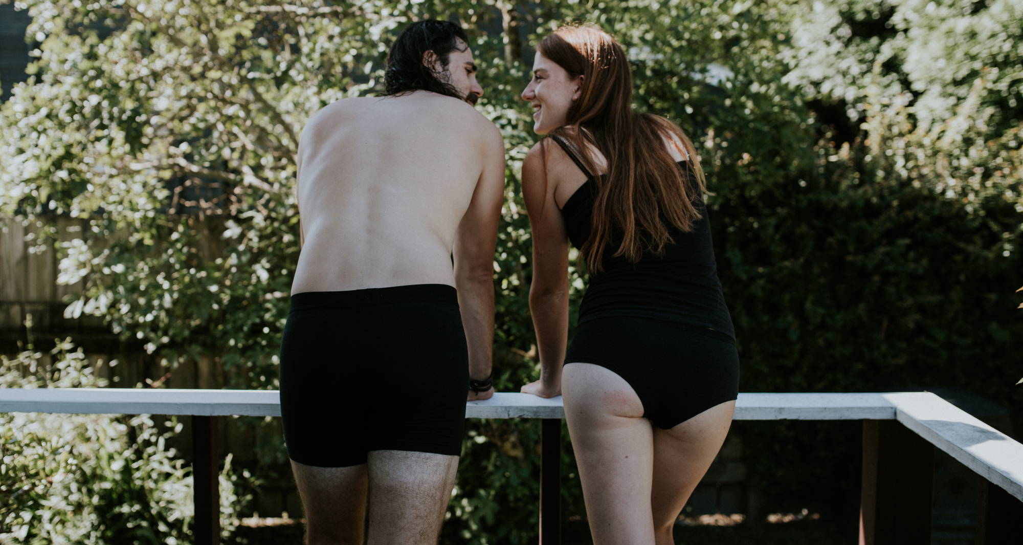 How often should you buy new underwear? A man and woman stand outside, leaning against a railing and smiling at one another.