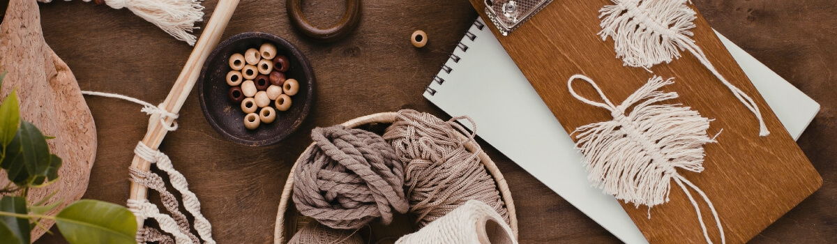 Crafting materials including yarn, a notebook, and decorative items on a table.