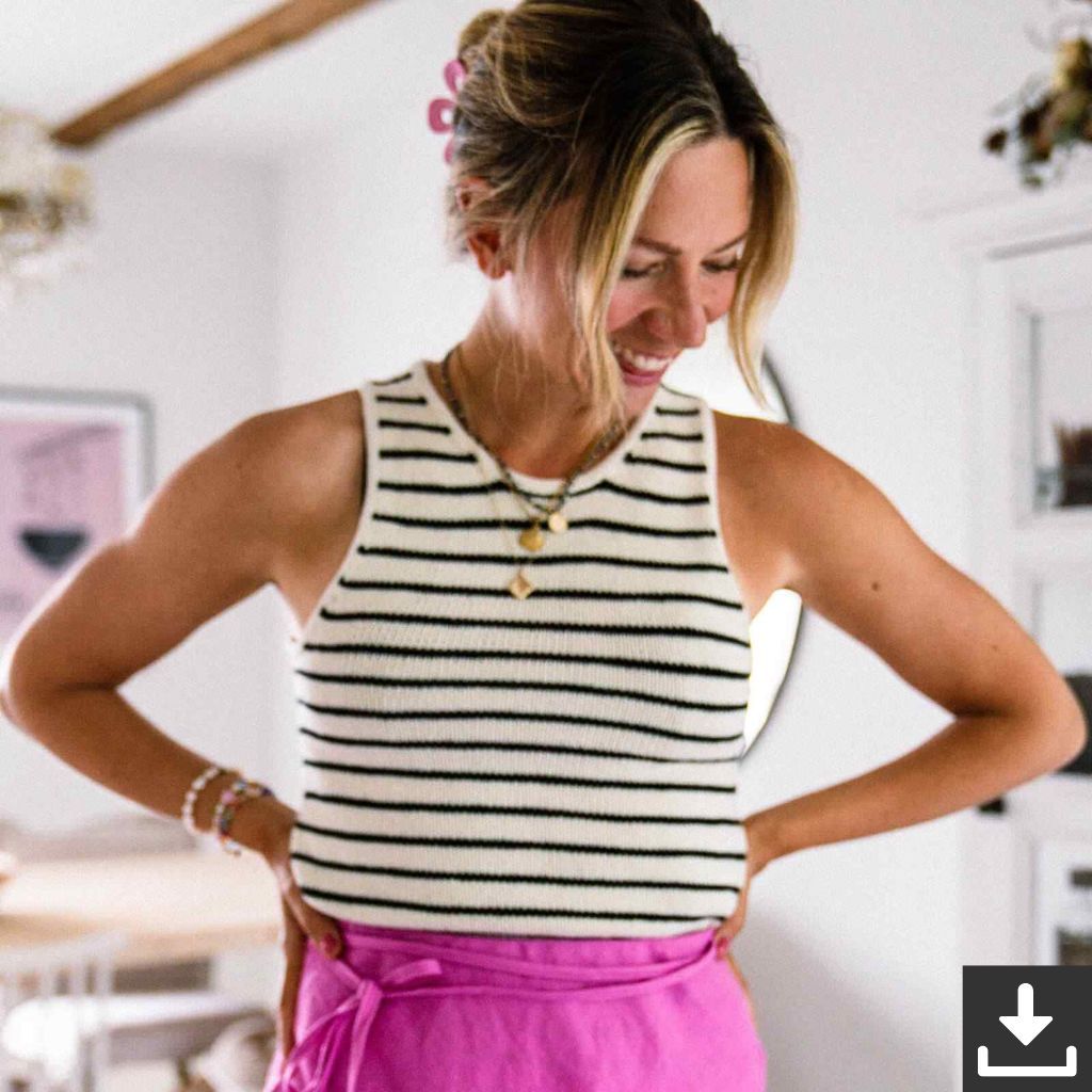 Eine Frau, die lächelt und ein gestreiftes Tanktop sowie einen rosa Rock trägt.