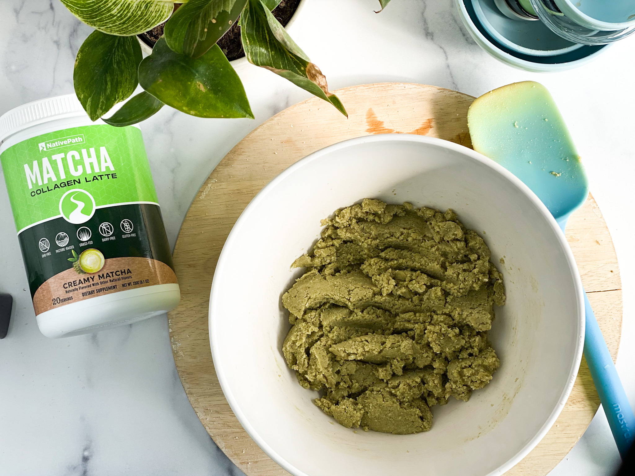 Paleo matcha collagen cookie mixture in a mixing bowl with a jar of Matcha Collagen on the side.