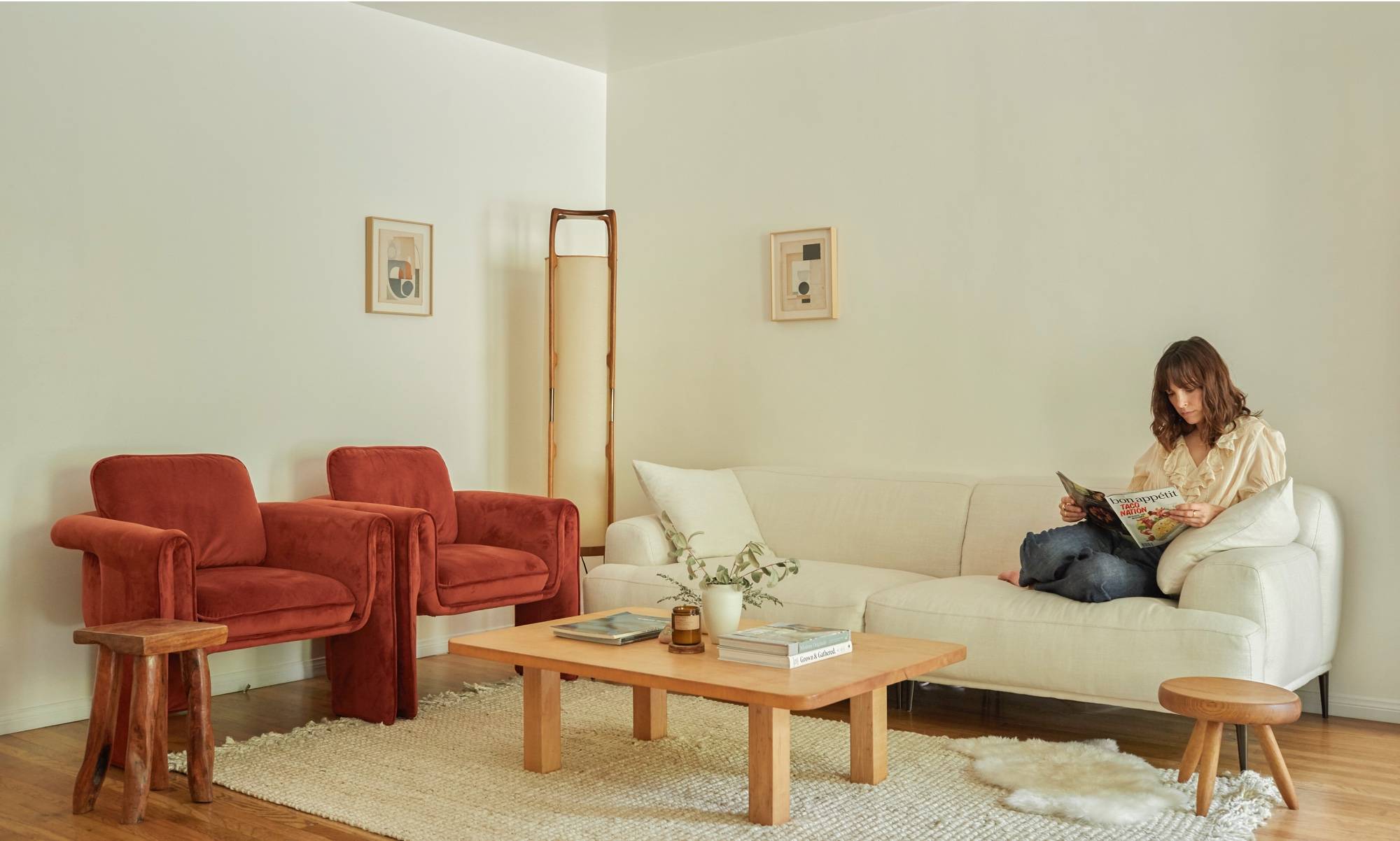 Long off-white low profile couch and two retro velvet chairs with antique stools