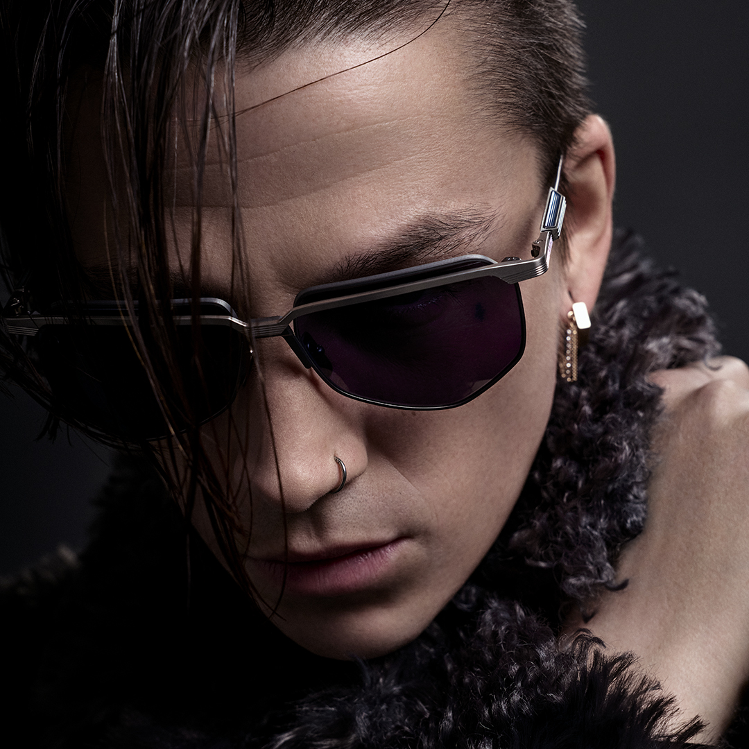 Young man with sunglasses and stylish hair, wearing a fur collar.