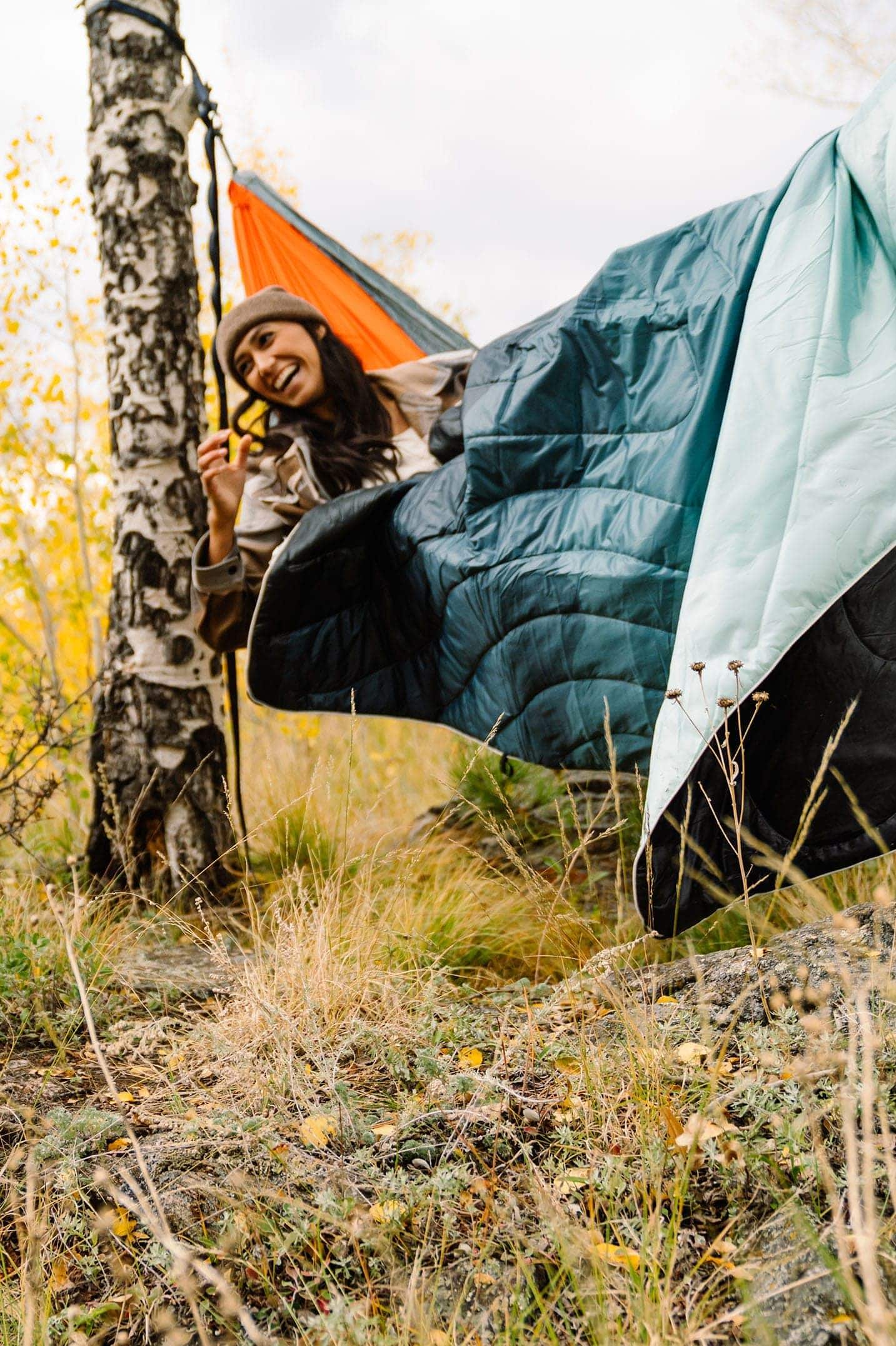 Woman sitting in a hammock under a Rumpl blanket