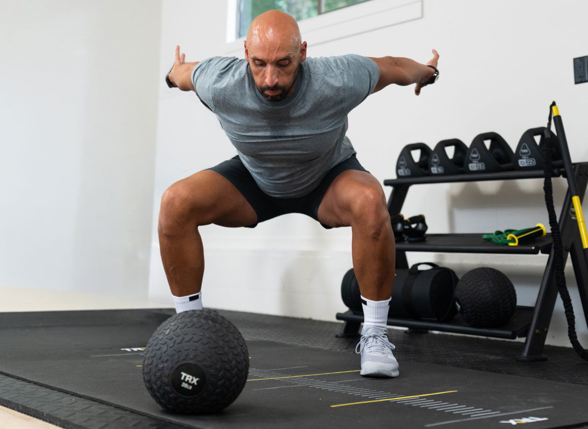 Man exercising with a medicine ball in a gym setting.