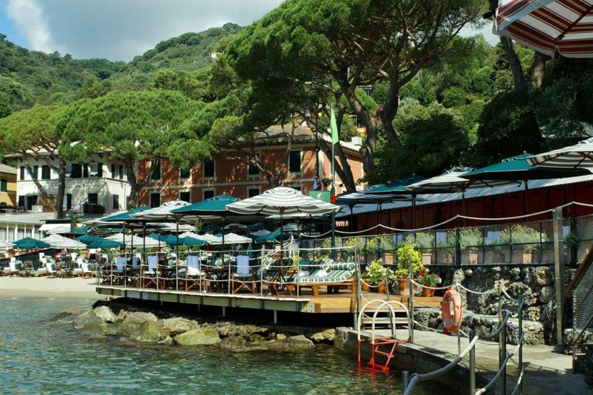 Scenic waterfront dining area with umbrellas and lush greenery.