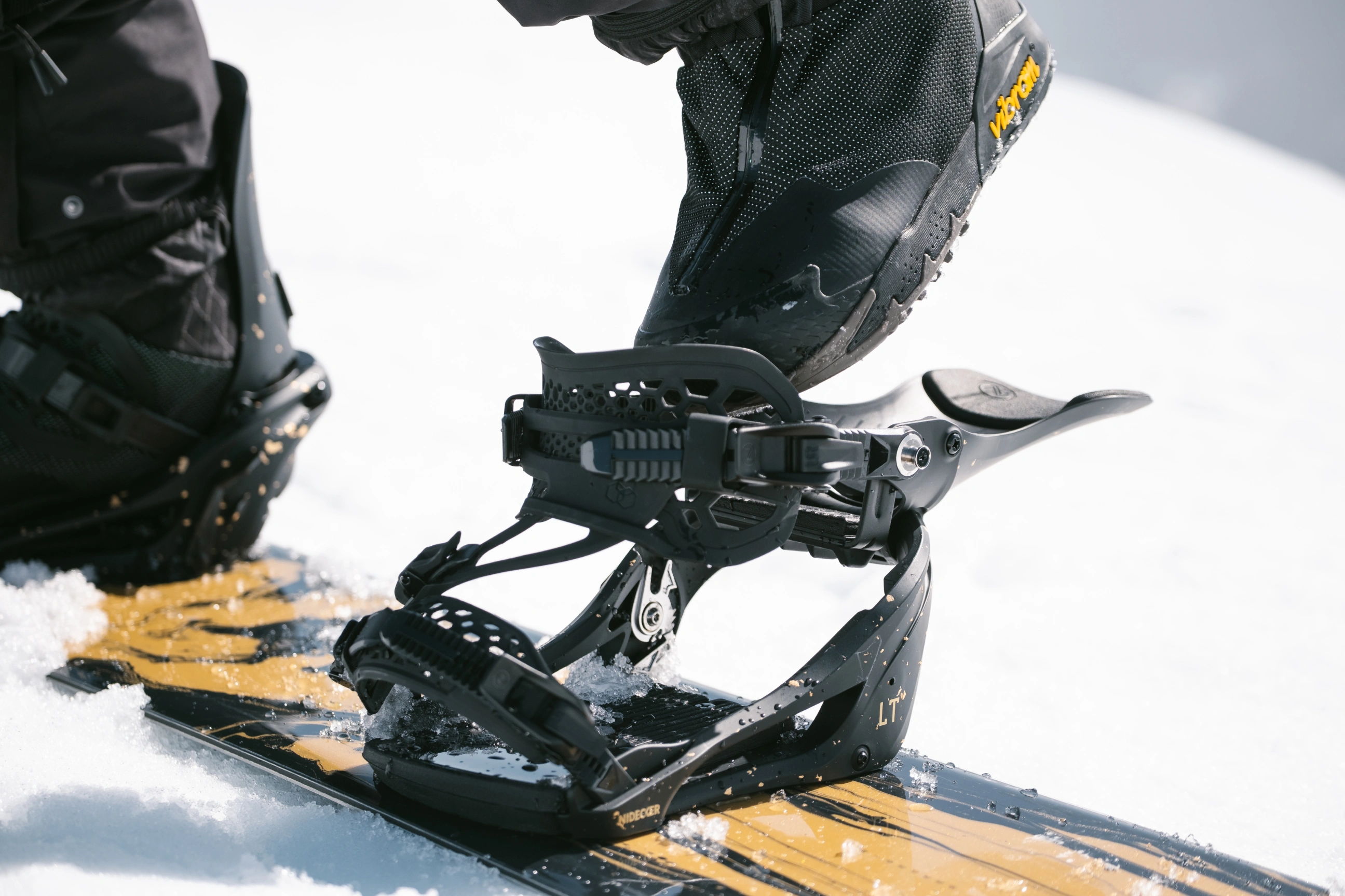 Close-up of a snowboard binding on a snowy surface.