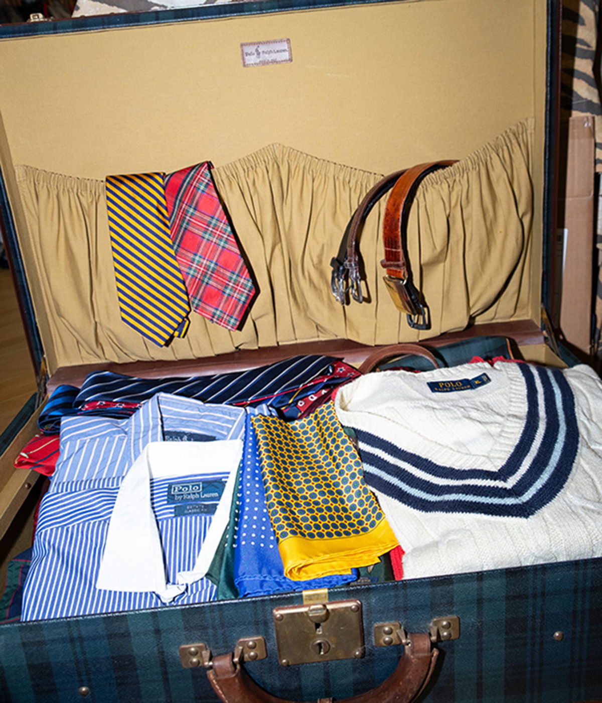 A suitcase filled with shirts, ties, and accessories neatly arranged.