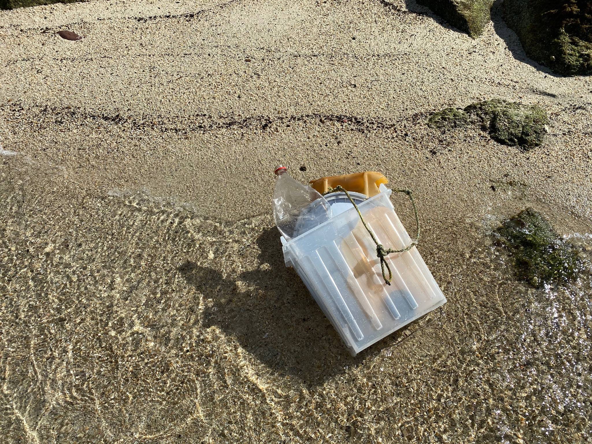 Garbage bin on beach holding ocean pollution
