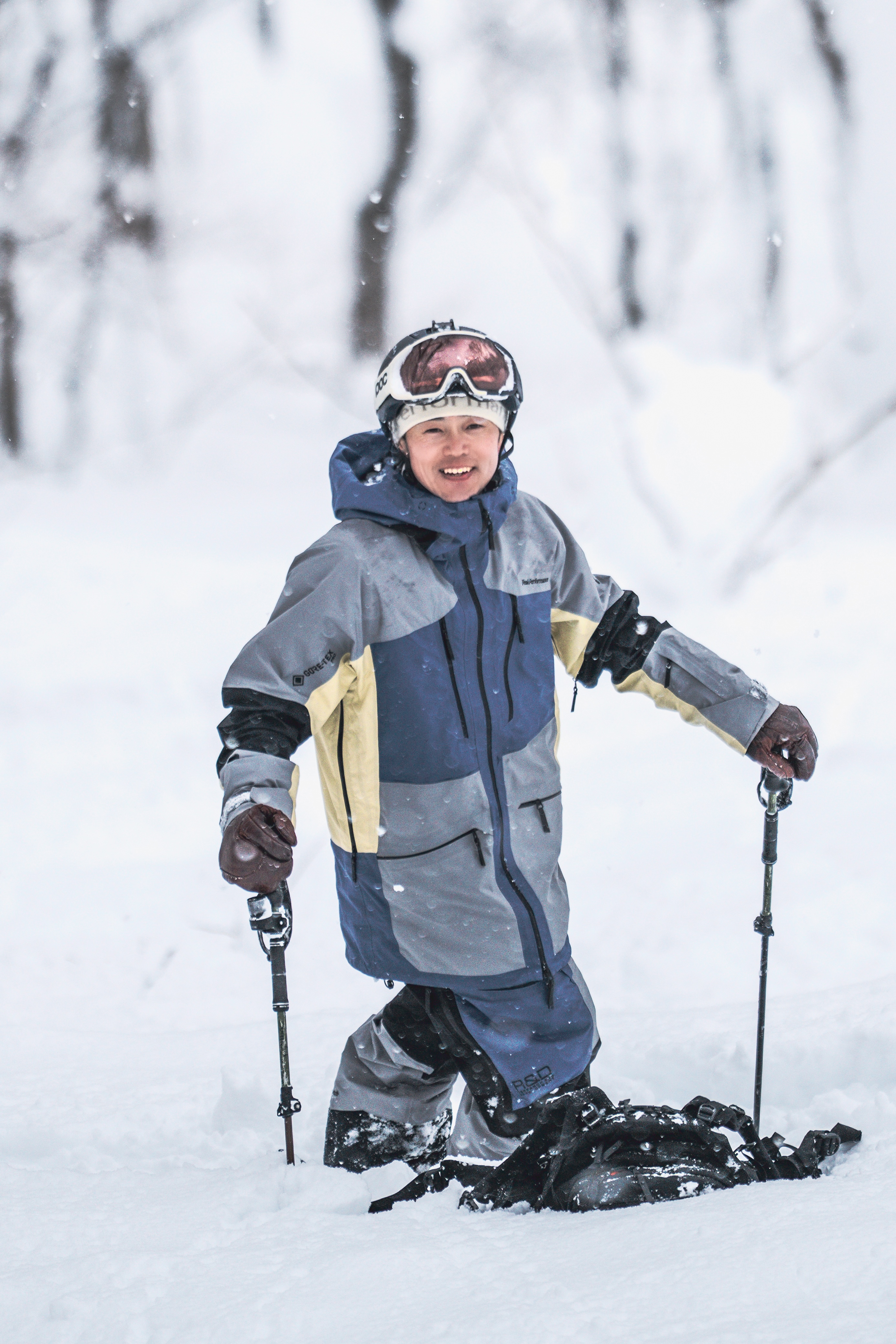 Child in ski gear smiling in snowy landscape.