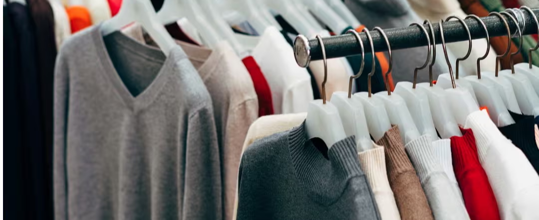 Rows of colorful sweaters hanging on hangers on a clothing rack