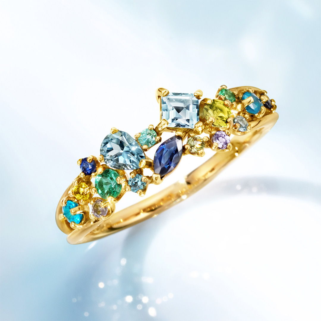 Gold ring adorned with colorful gemstones on a light background.