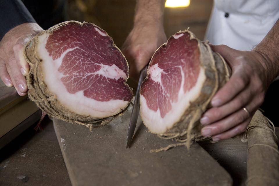 A rare culatello ham is cut in half to reveal pink meat