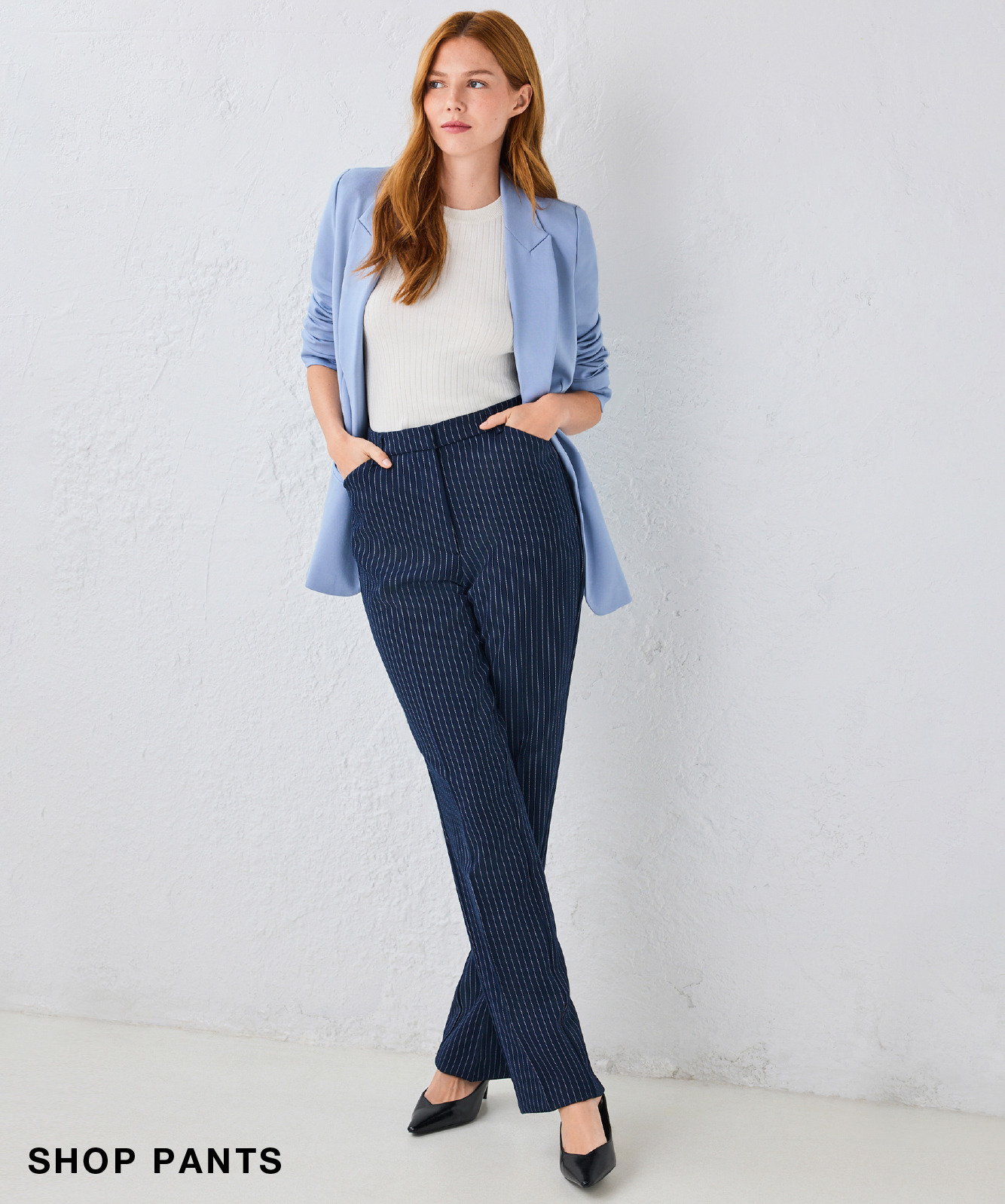Woman in a blue blazer and white top, wearing navy pants and heels.