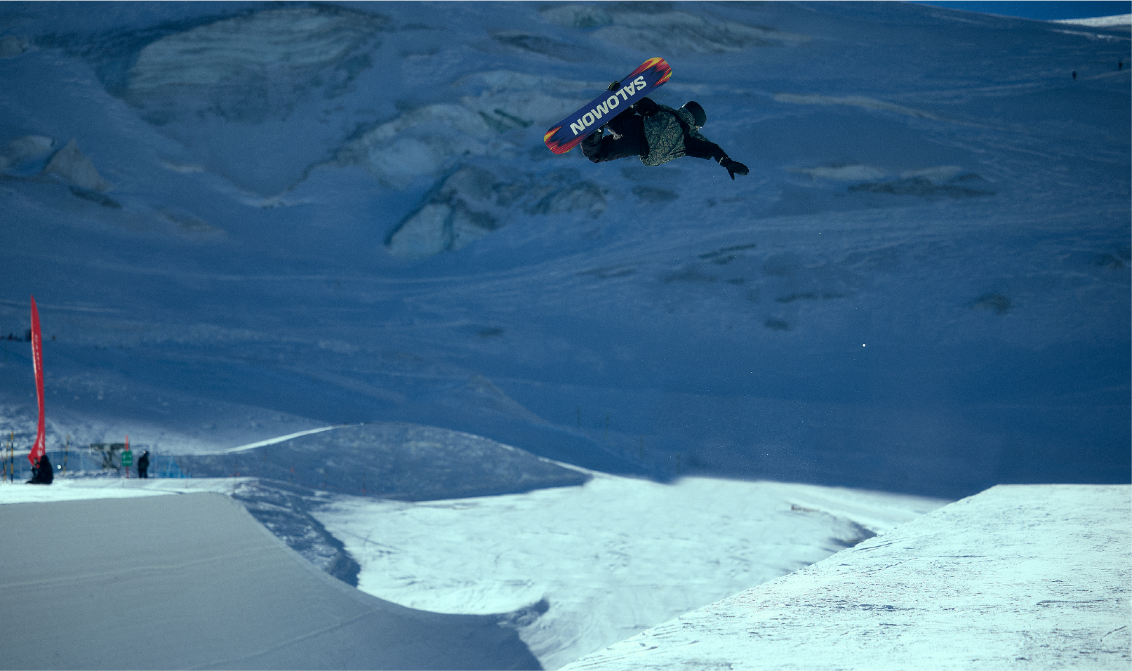 A snowboarder performing a jump in a snowy landscape.