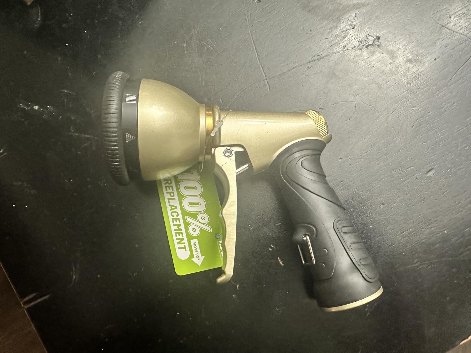 A gold and black spray nozzle on a dark surface.