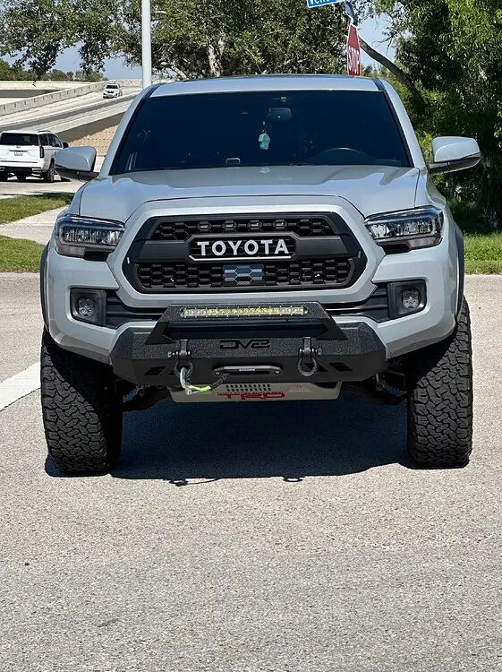 Front high-angle gray Toyota Tacoma TRD TOYOTA grille DV8 winch bumper LED light bar TRD skid plate Bruce's Stealth spare tire delete featured gallery photo 1