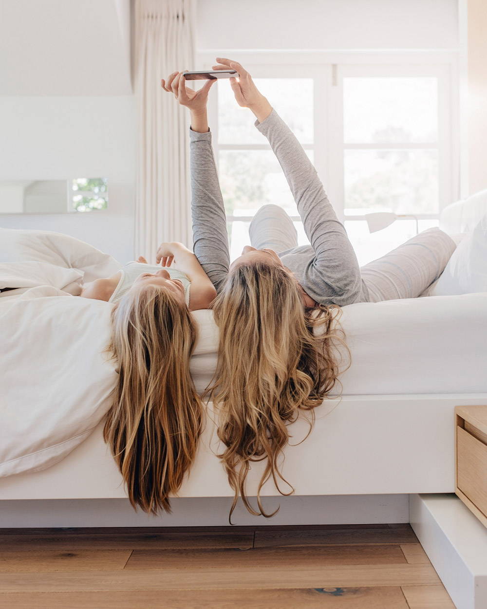 How to help your teen sleep better - image shows two girls lying on a bed and looking at a phone
