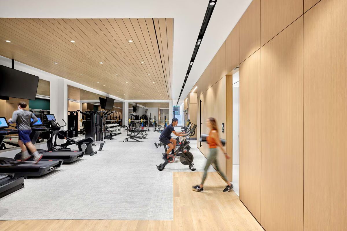 Modern gym interior with exercise equipment and individuals working out.