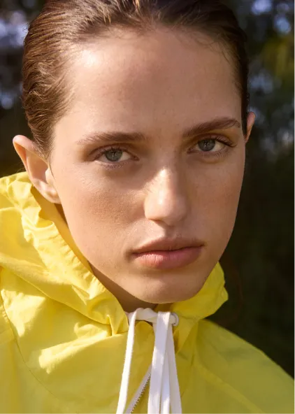 Person wearing a yellow jacket with a serious expression outdoors.
