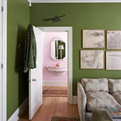 A vibrant sage green room leading to a bathroom painted pink.