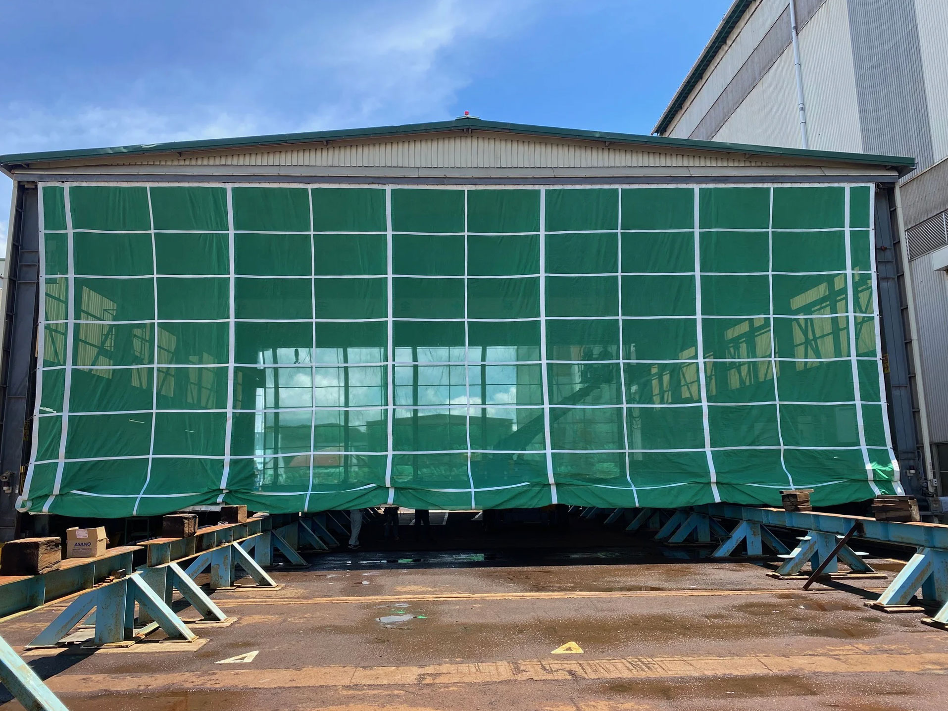 Green mesh covering a building with blue sky in the background.