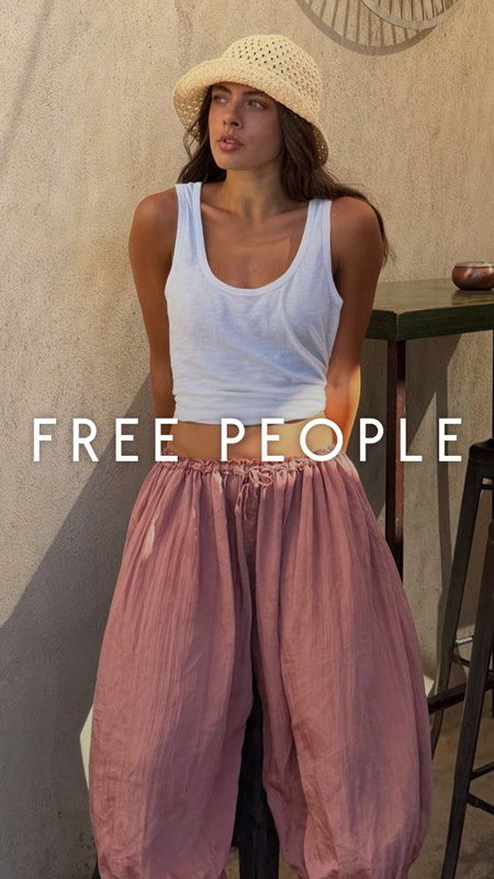 Model wearing a white tank top and pink baggy pants, with a hat.