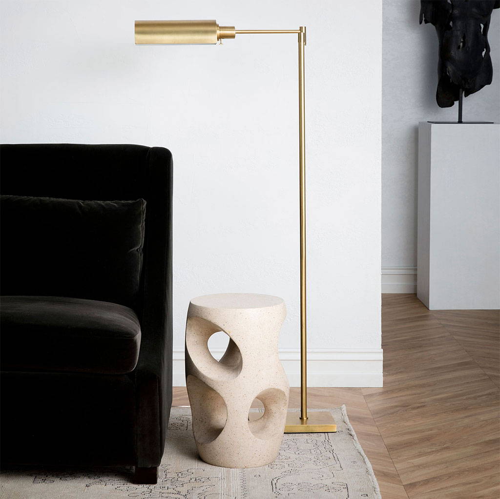 Library floor lamp beside a velvet couch and a sculptural side table