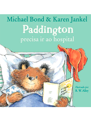 Paddington bear reading in bed, with a red hat beside him.