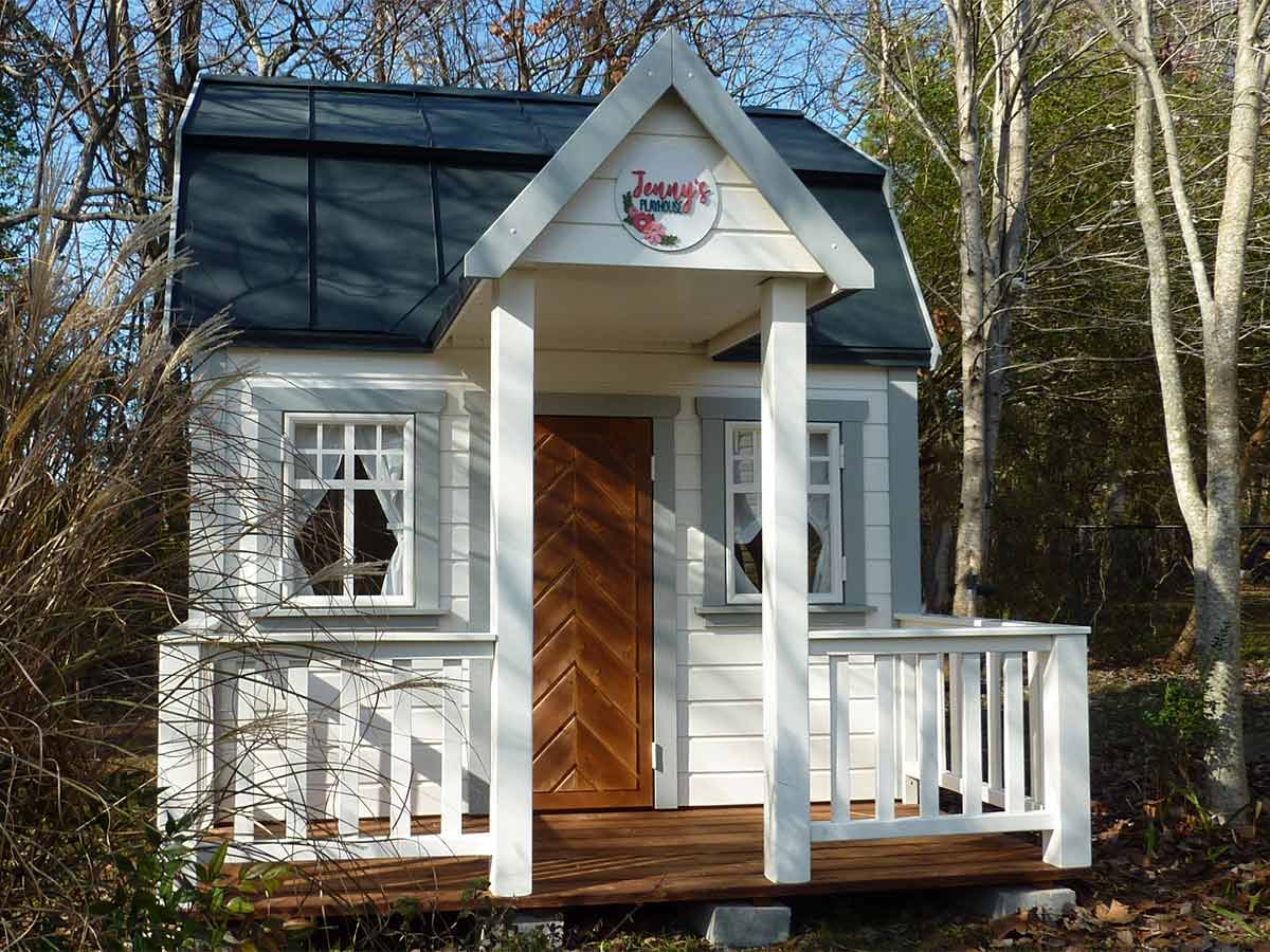 Modern farmhouse style Wooden Playhouse with Gambrel roof and wooden porch with railing by WholeWoodPlayhouses