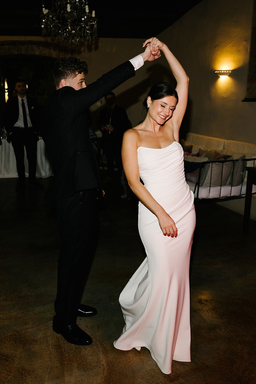 A couple dancing at a celebration, with elegant attire and joyful expressions.