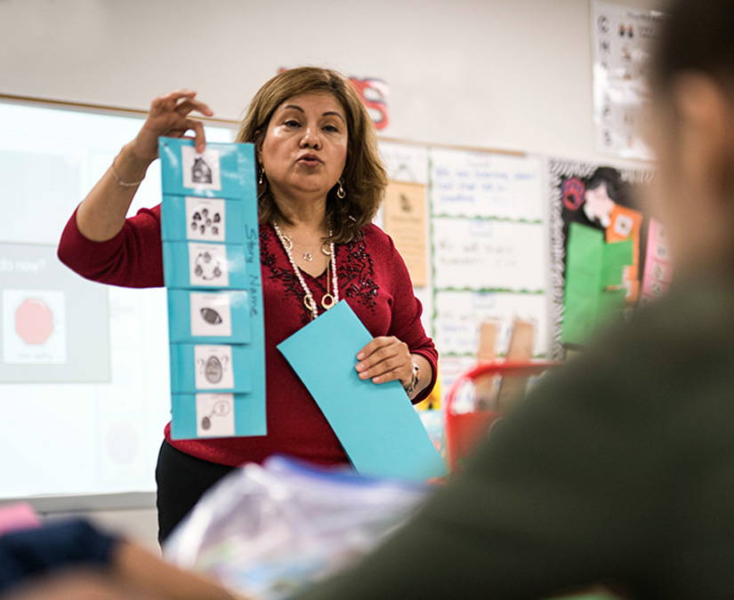 Teacher showing Boardmaker 7 PCS symbol print material to students in a classroom.