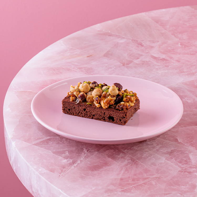 Caramel and mixed nut brownie on pink background