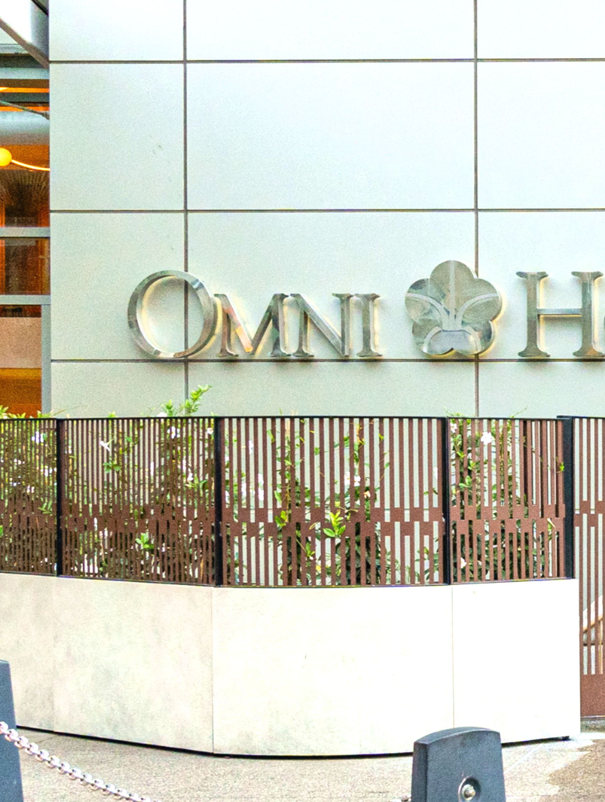 Signage for Omni Hotel with decorative plants and modern architecture.