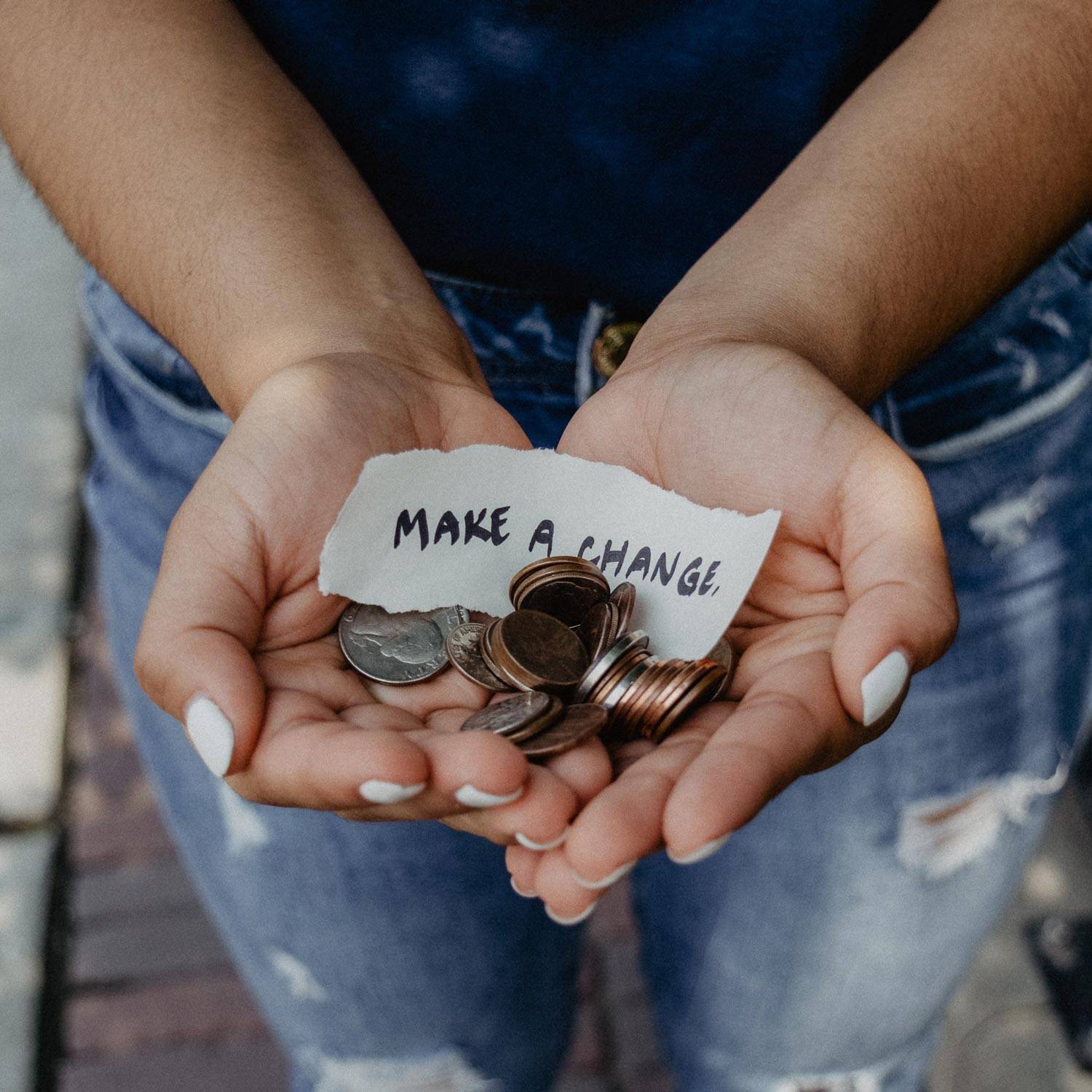 Someone holding some loose coins and a note saying 'make a change'.