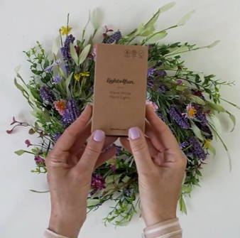A person holiding a box of micro lights over her spring wreath.