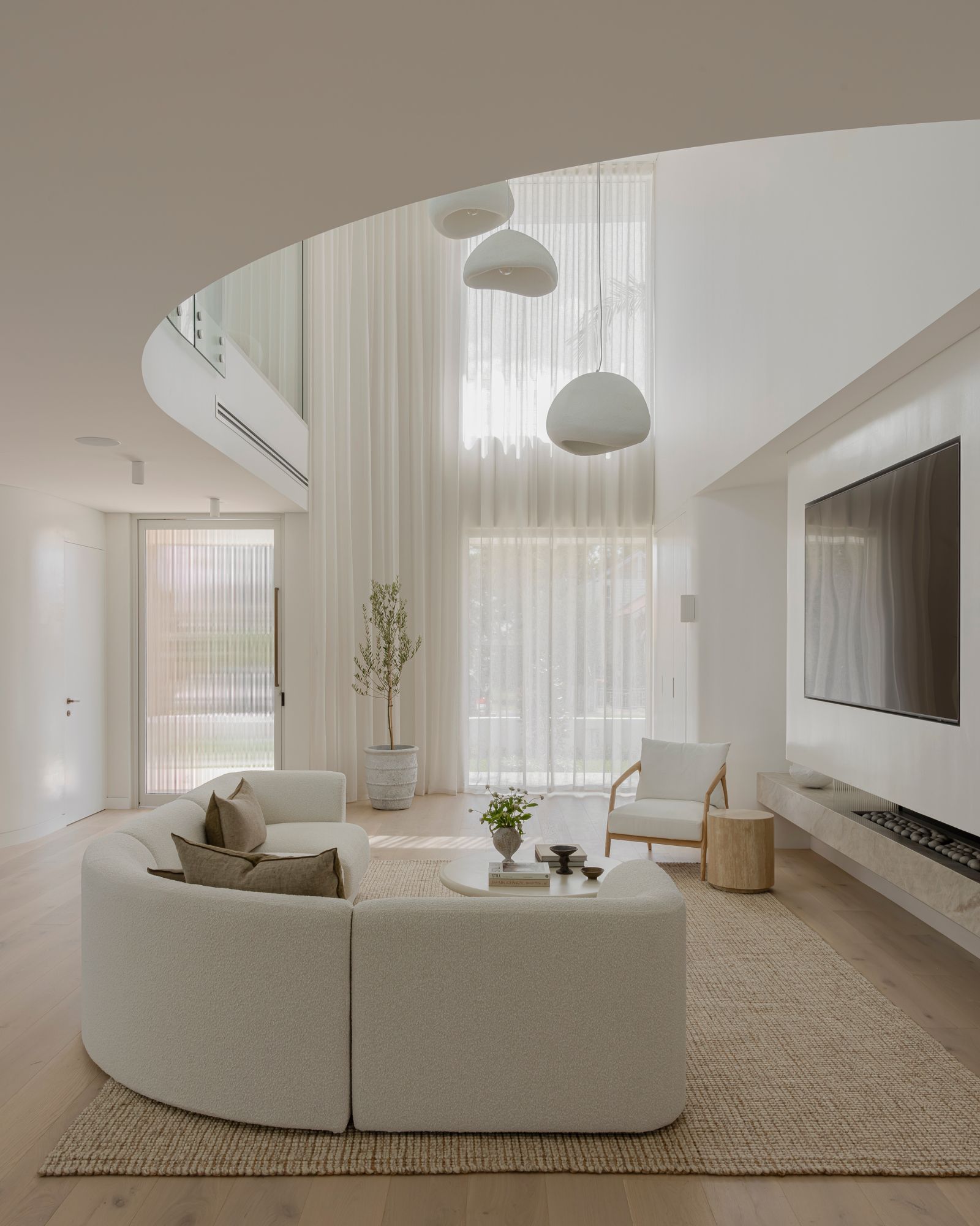 Modern living room with white curved sofa and a cluster of pendant lights