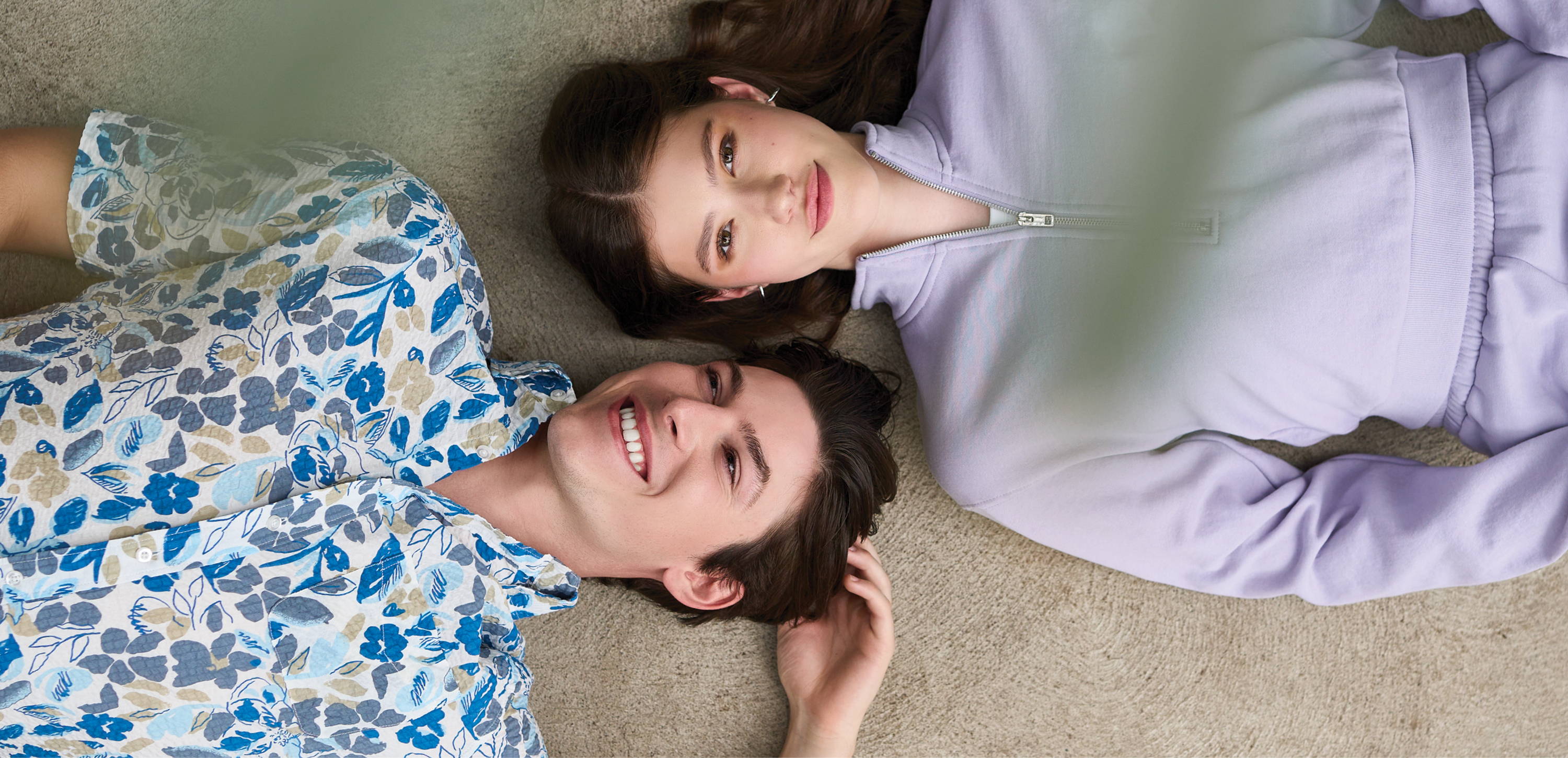 Tall man and woman laying with their heads beside one another wearing American Tall clothing