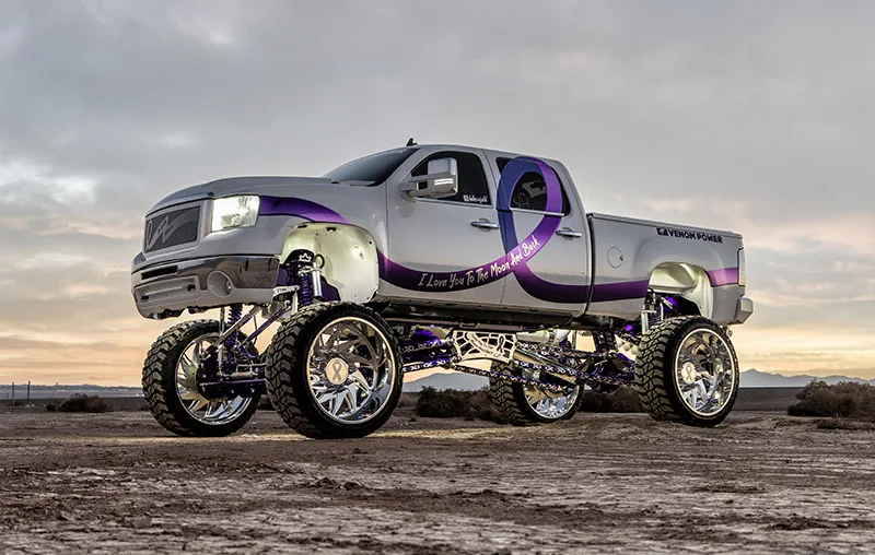 Lifted white GMC truck side view with purple ribbon graphics