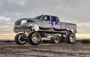 Lifted white GMC truck side view with purple ribbon graphics