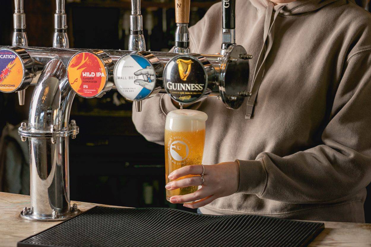 A barmaid pulls a pint of beer