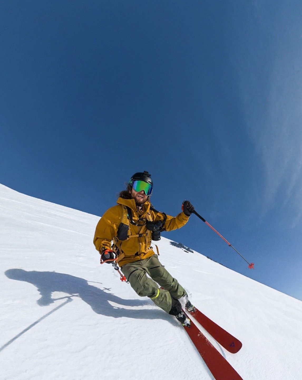 Person skiing on snow-covered slope against a clear blue sky