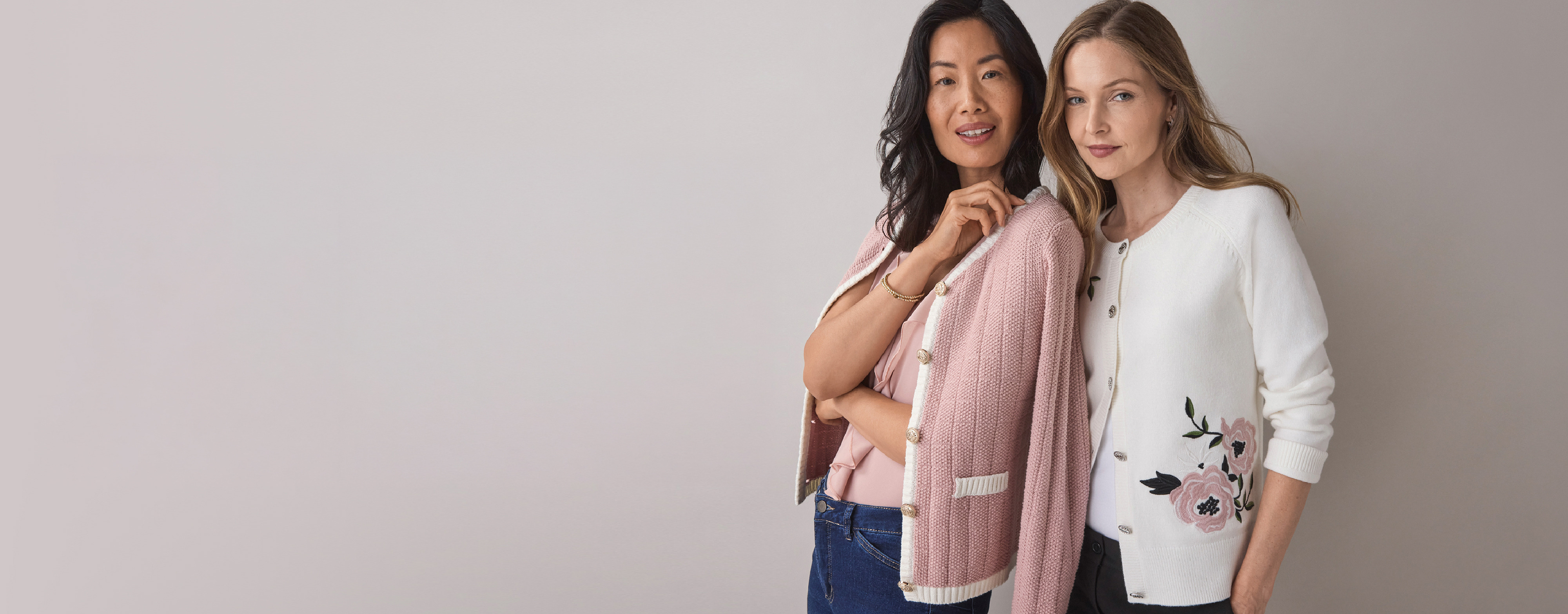 Two women posing in stylish sweaters against a light background.