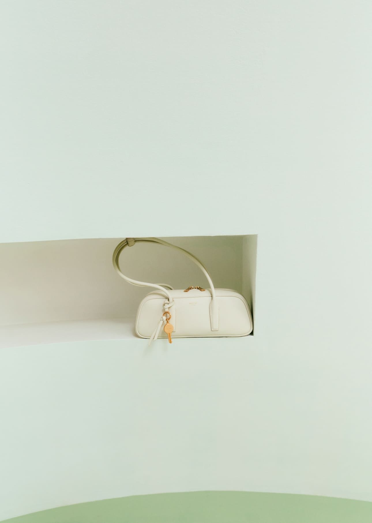 A small cream handbag displayed on a light green background.