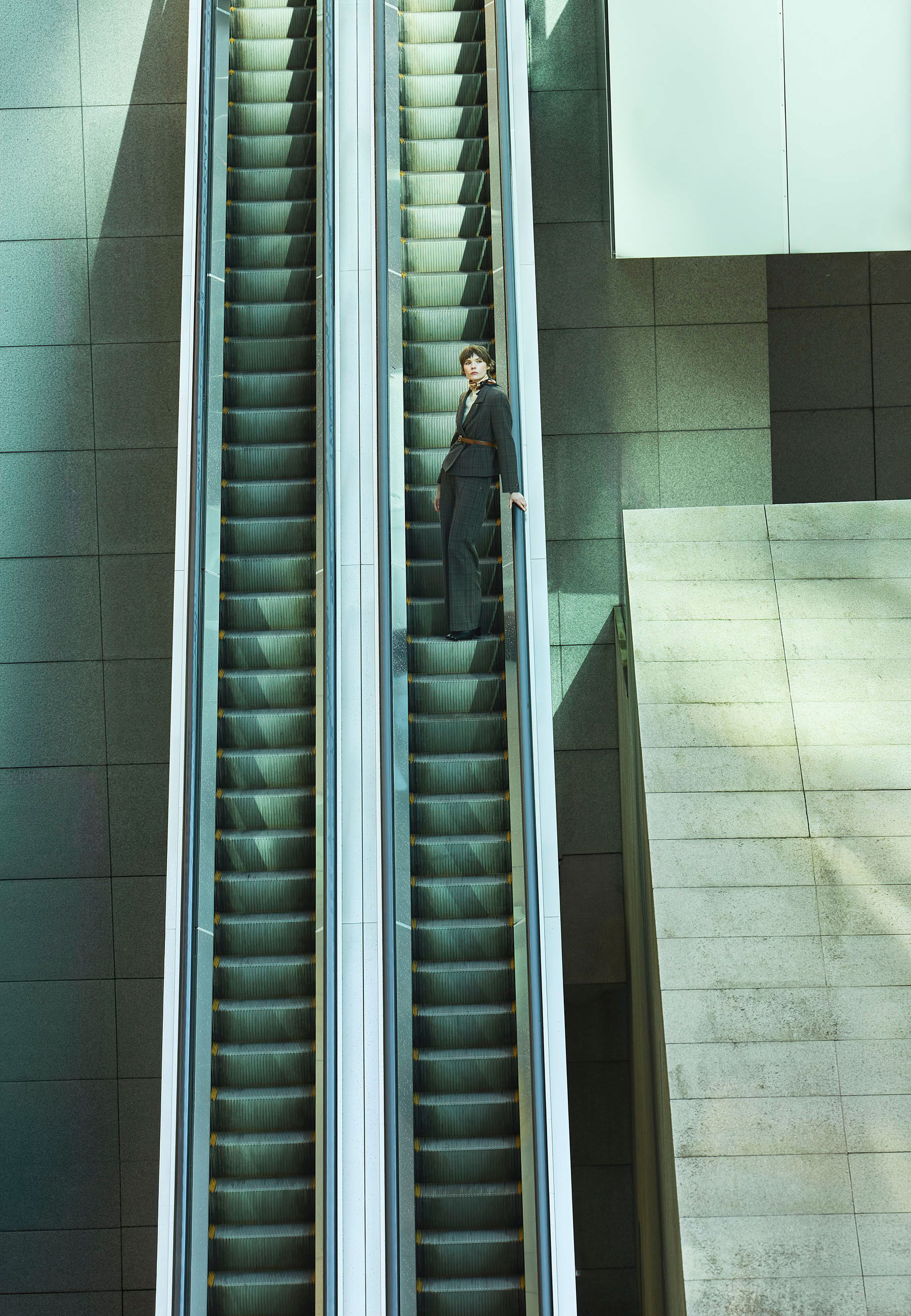 A person standing on an escalator in a modern building.