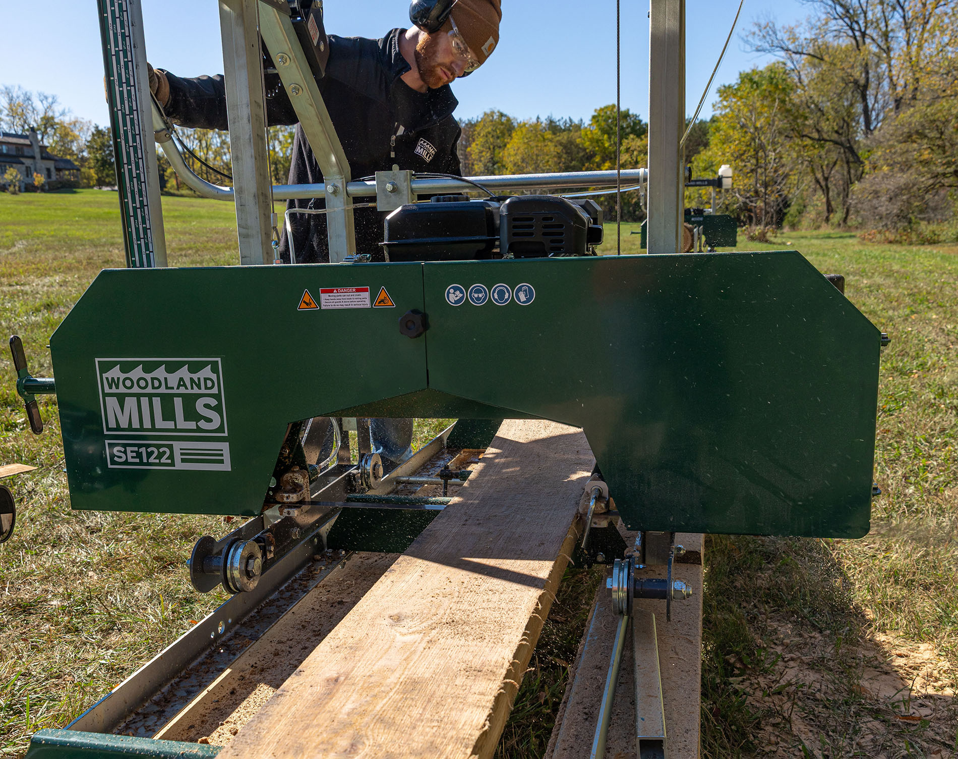 Person operating a Woodland Mills SE122 Portable sawmill with a large piece of wood on the machine.