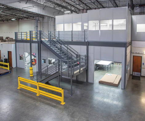 Two story inplant office installed on mezzanine in industrial setting.