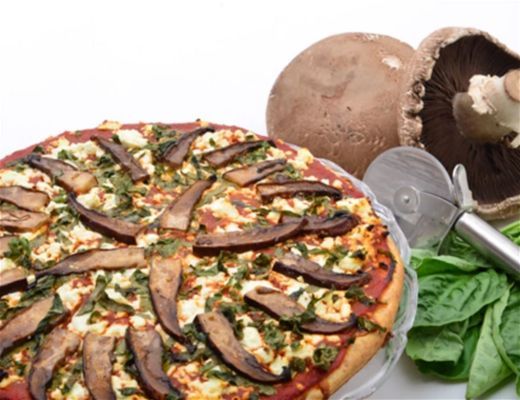 A pizza topped with mushrooms and spinach on a white background.