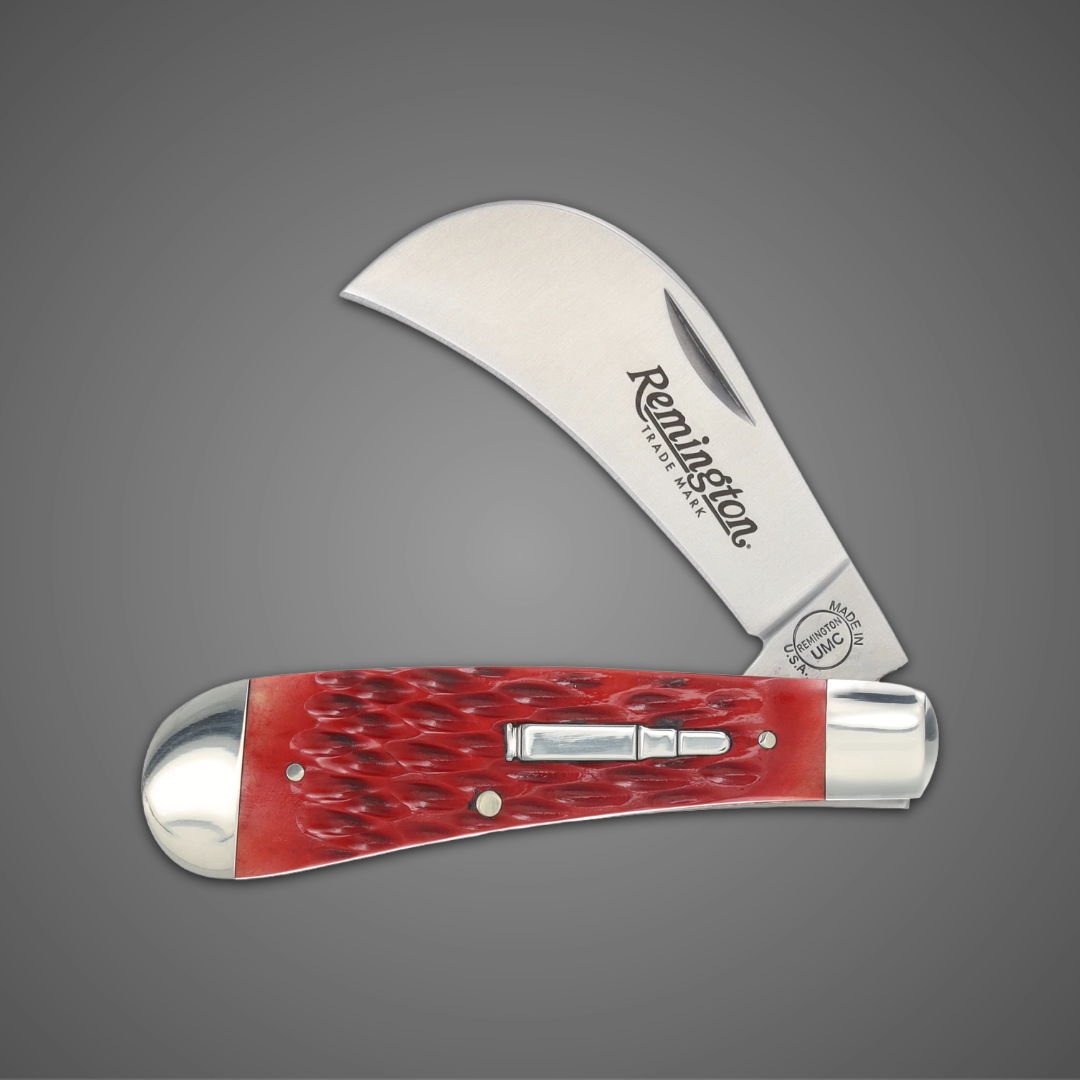 A folding knife with a curved blade and red handle.
